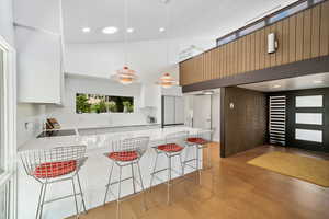 Kitchen with a kitchen breakfast bar, natural light, electric cooktop, white cabinets, pendant lighting, and light flooring