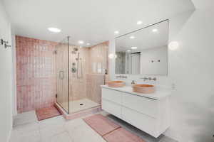 Bathroom with mirror, shower with glass door, and dual bowl vanity