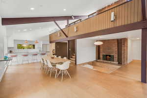 Dining area featuring a kitchen bar, beamed ceiling, and a brick fireplace