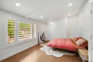 Bedroom featuring vaulted ceiling with beams and natural light