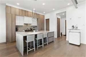 Kitchen with a kitchen bar, light hardwood floors, light countertops, and white cabinetry