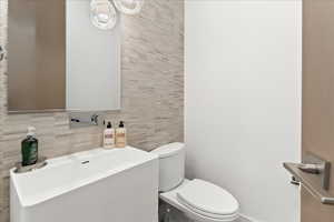 Half bath with toilet, mirror, and washbasin