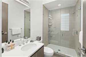 Full bathroom with oversized vanity, shower booth, mirror, and toilet