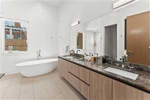 Bathroom with tile flooring, double sink vanity, mirror, and a tub
