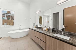 Bathroom with tile flooring, double sink vanity, mirror, and a tub