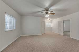 Carpeted spare room featuring a ceiling fan and natural light
