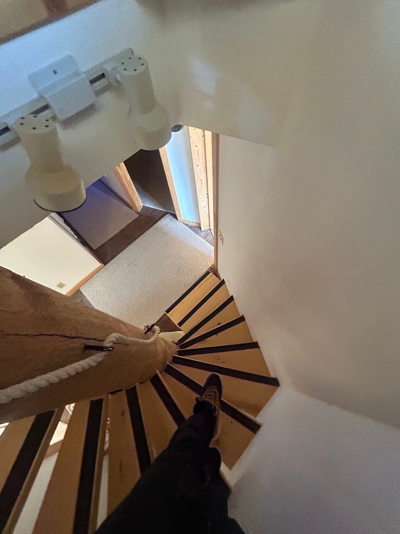 Spiral wood-finish staircase featuring a central wood column and rope handrail