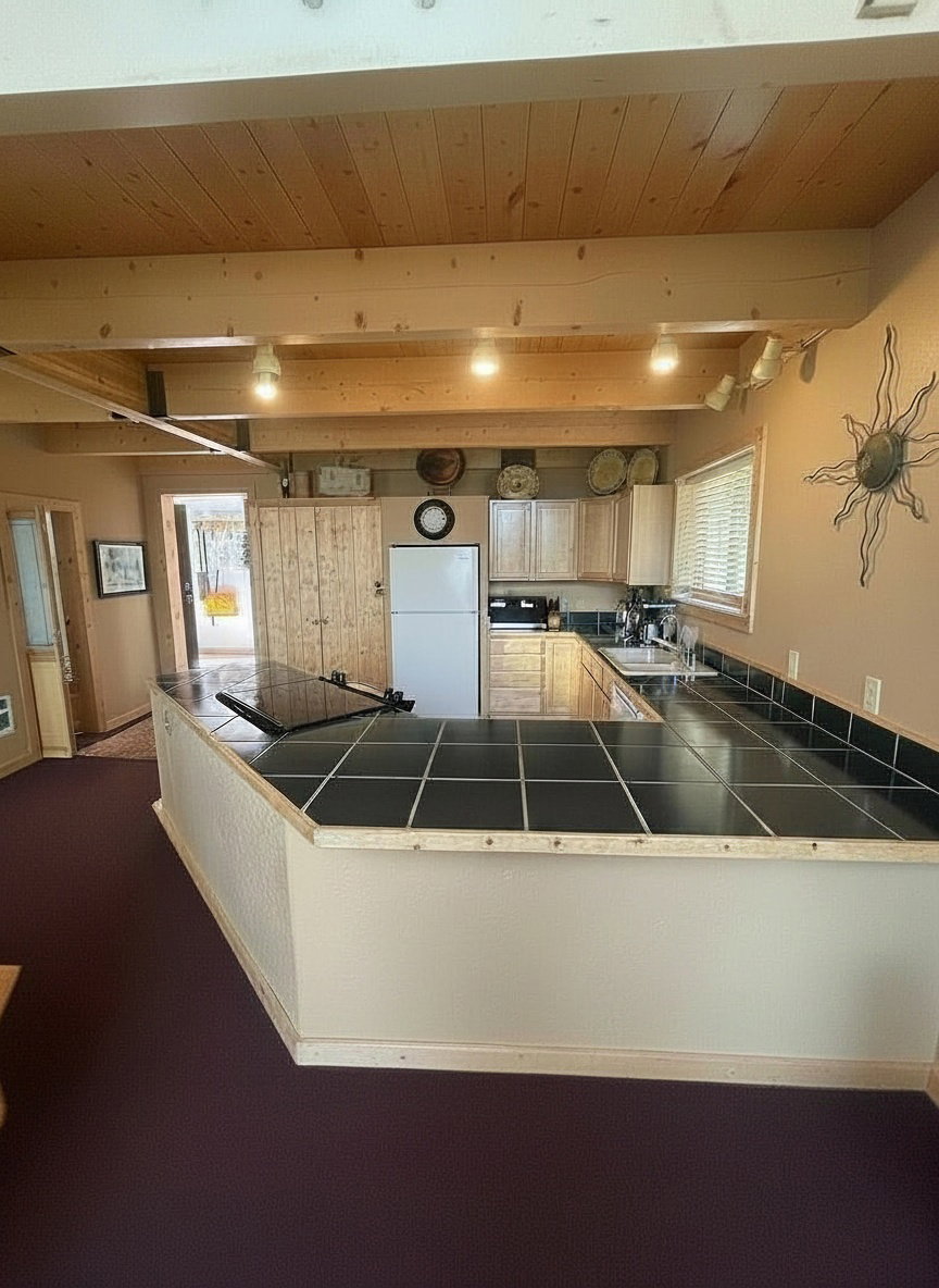 Kitchen area featuring a U-shaped counter with green tile surfacing, light wood cabinetry, and a beamed wood-finish ceiling
