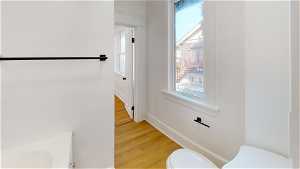 Unit 1 Half bath featuring hardwood floors, natural light, vanity, and toilet