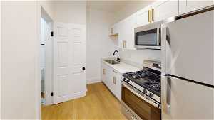 Unit 3 Kitchen featuring gas range oven, stainless steel microwave, refrigerator, and light hardwood floors