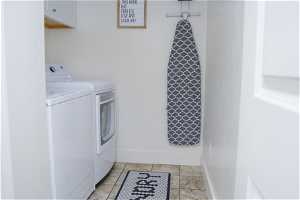 Washroom with tile flooring and washer / dryer