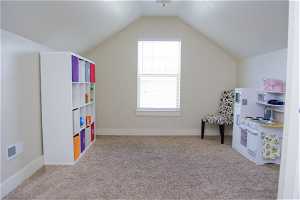 Playroom featuring vaulted ceiling, carpet, and natural light