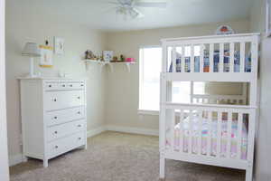 Carpeted bedroom with a ceiling fan and natural light