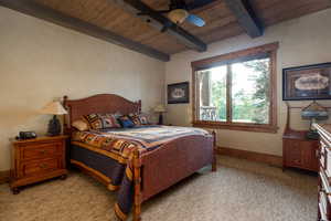 Bedroom featuring beamed ceiling, baseboards, ceiling fan, light colored carpet, and wood ceiling