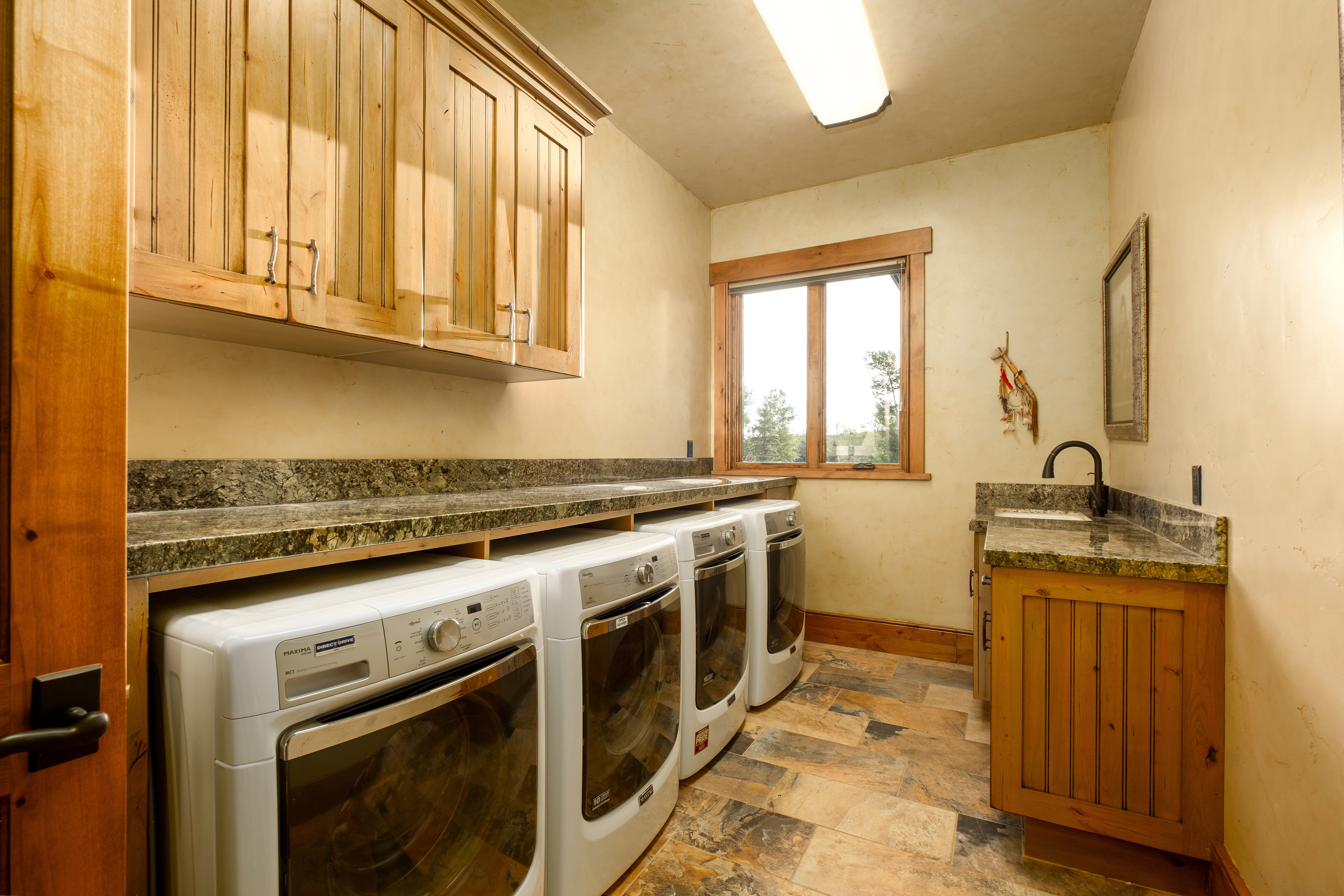 Washroom featuring cabinet space, a sink, stone finish floor, baseboards, and washer and clothes dryer