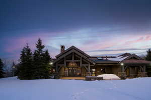 View of front of home with a chimney, a patio, stone siding, french doors, and roof mounted solar panels