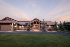View of front of house with a garage, a front lawn, driveway, and stone siding