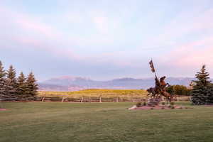 Yard at dusk with a mountain view, a rural view, and fence