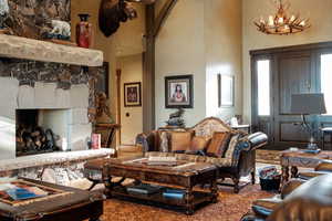 Living area with arched walkways, a high ceiling, a fireplace, and a notable chandelier