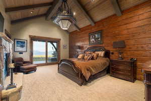 Bedroom featuring wood walls, beamed ceiling, light colored carpet, and access to exterior