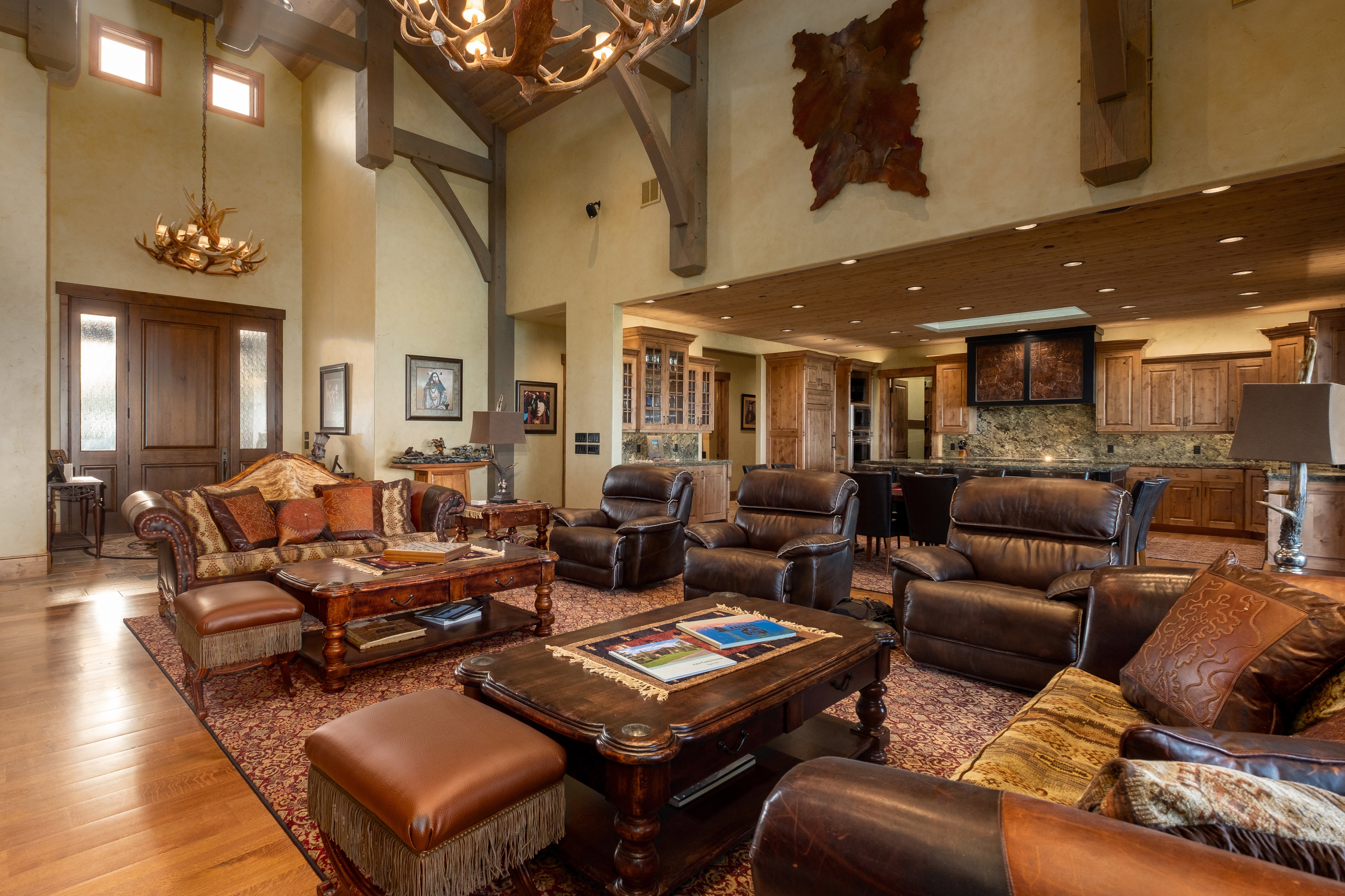 Living area with light wood-style floors, recessed lighting, a towering ceiling, and a notable chandelier