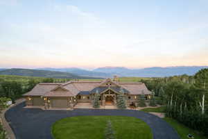 View of front of house with a garage, a mountain view, a chimney, and driveway