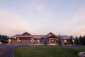 View of front of property featuring a lawn, driveway, stone siding, and a garage