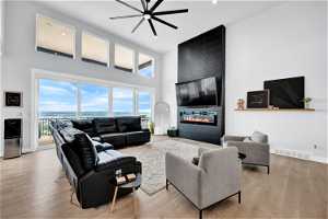 Hardwood floored living room with a fireplace, a ceiling fan, natural light, and TV