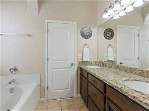 Bathroom featuring tile floors, mirror, a tub, and dual bowl vanity