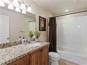 Full bathroom featuring shower curtain, vanity with extensive cabinet space, tub / shower combination, mirror, and toilet