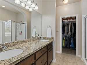 Bathroom with tile floors, his and hers vanity, shower with shower door, and mirror