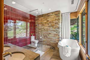 Bathroom featuring plenty of natural light, hardwood flooring, separate shower and tub enclosures, his and her basins, and toilet