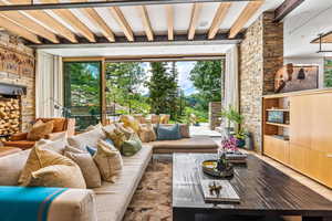 Living room featuring beamed ceiling, a fireplace, and plenty of natural light