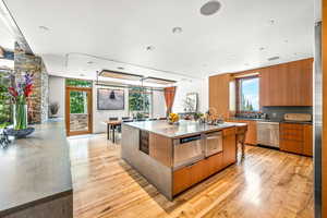 Kitchen with natural light, dishwasher, light hardwood floors, light countertops, and brown cabinetry