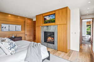 Hardwood floored bedroom featuring a fireplace and natural light