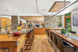 Kitchen with a breakfast bar, natural light, stainless steel finishes, light hardwood flooring, and brown cabinets