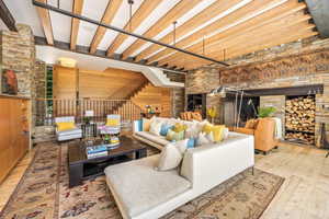 Living room with a fireplace, beamed ceiling, and hardwood floors