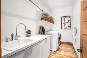 Laundry area with wood-type flooring and washer / dryer