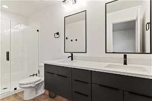 Full bathroom featuring mirror, toilet, double large vanity, and enclosed shower