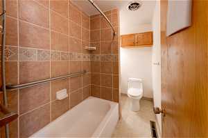 Bathroom with tile flooring, toilet, and shower / bathing tub combination