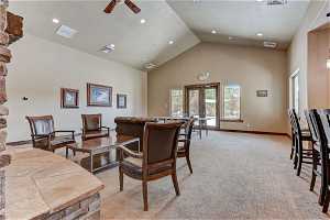 Carpeted dining area featuring a high ceiling, lofted ceiling, and ceiling fan