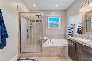 Bathroom with mirror, light tile flooring, vanity, and separate shower and tub enclosures