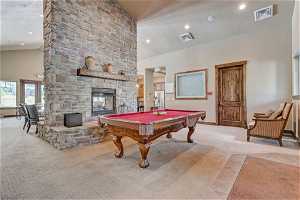 Game room featuring light carpet, lofted ceiling, a high ceiling, and a fireplace