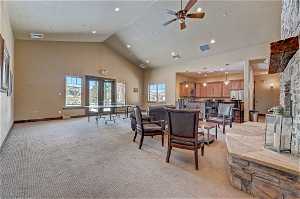 Living room featuring light carpet, vaulted ceiling, a high ceiling, and ceiling fan