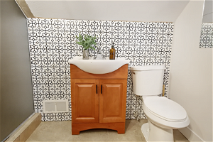 Bathroom with tile walls, an enclosed shower, vanity, and light tile floors