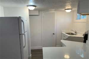 Kitchen featuring dark parquet floors, a textured ceiling, and white fridge