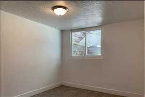 Unfurnished room with a textured ceiling and carpet floors