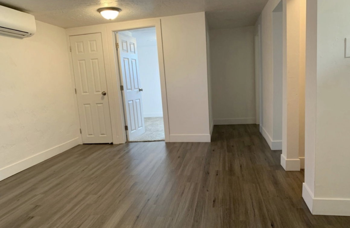 Empty room with a textured ceiling, a wall mounted air conditioner, and light parquet floors