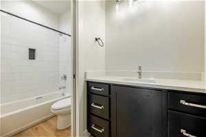 Full bathroom with vanity, light hardwood flooring, and tiled shower / bath combo