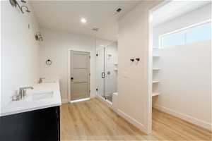 Owner's Bathroom featuring light LVP flooring, a shower with shower door, and double vanity